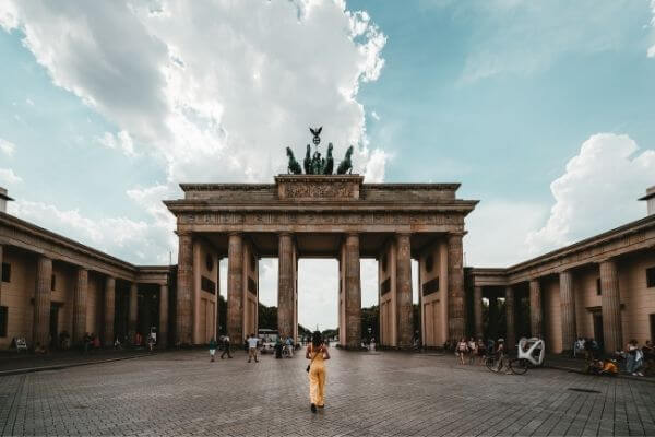 Chica vestida con un mono amarilla delante de la puerta de brandenburgo en Berlín