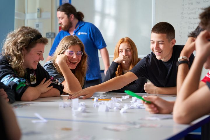 Participantes del campamento de verano en Inglaterra con alojamiento en familia pasándolo genial realizando un juego en grupo en una clase de inglés