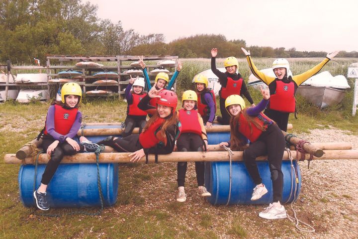 Grupo de adolescentes en un campamento de verano realizando una barca con elementos cuotidianos