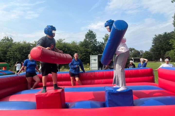jóvenes del grupo de verano en Colchester participando en una pelea en un hinchable