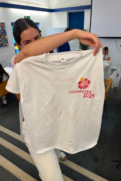 participante del campamento de inglés en Inglaterra enseñando una camiseta pintada que ha hecho en una actividad