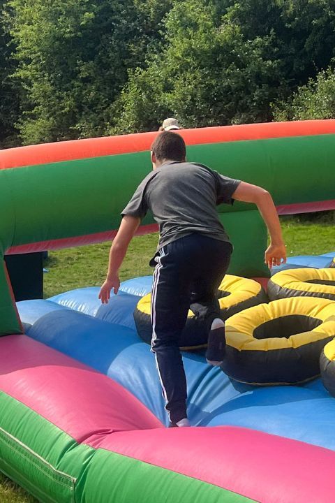 Participante del campamento de verano en Inglaterra realizando una carrera de obstáculos en un hinchable