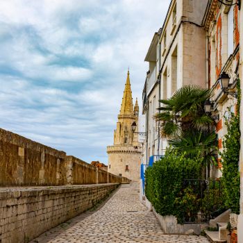 Calle adoquinada  con un muro de piedra en el lado izquierdo en La Rochelle, Francia