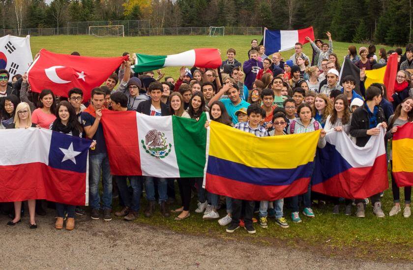 Grupo de estudiantes adolescentes con banderas de diferentes países en el patio del instituto