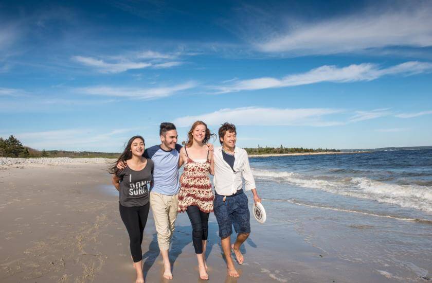 Cuatro estudiantes paseando en la playa de Nueva Escocia