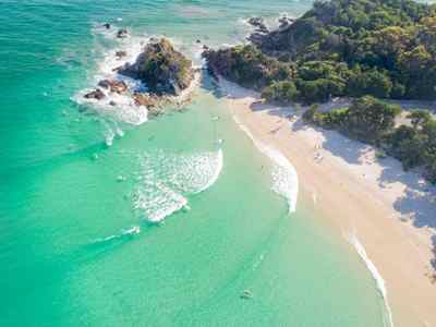 Vista aerea de la costa con personas haciendo surf en Byron Bay, Australia