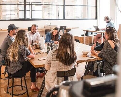 Grupo de personas adultas reunidas alrededor de una mesa, vestidas de forma informal.