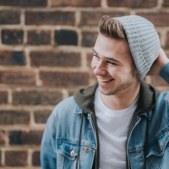 Chico joven con gorro de lana gris sonriendo