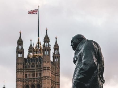 Primer plano picado con la imagen de la estátua de Winston Churchill y el parlamento inglés de fondo, en Londres