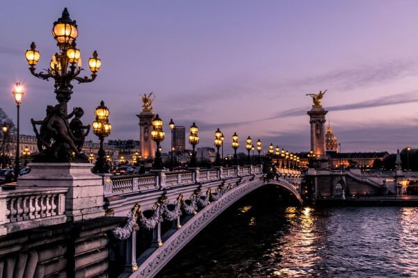 puente de París con luces encendidas y cielo al atardecer