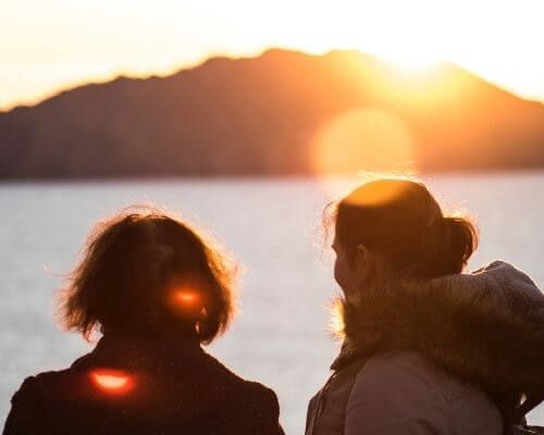 Dos mujeres de espaldas a contraluz mirando hacía las islas cíes