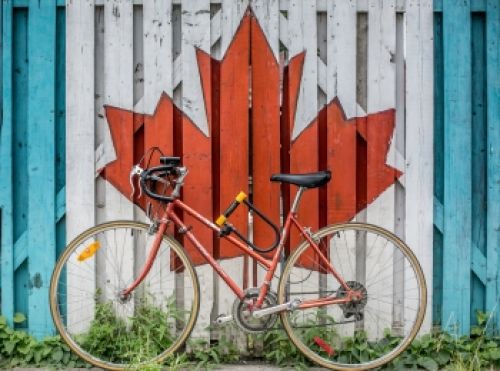 Bicicleta apoyada en una verja con el dibujo de una hoja de arce típica de Canadá