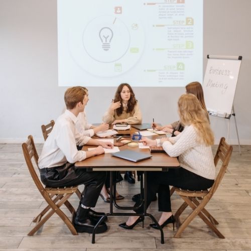 Estudiantes compartiendo ideas en una mesa rectangular en uno de los programas especializados en Australia que dan derecho a trabajar en el país